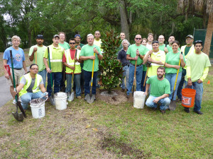 Participants of the tree planting event in Temple Terrace, including Tampa Electric team members in their green CommUnity T-shirts, gather around a magnolia tree that they planted. 